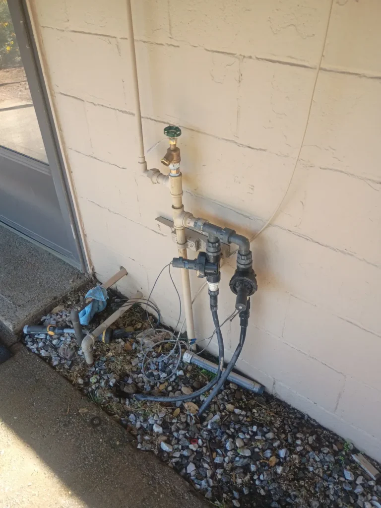 The irrigation valve and water-line connections behind the house.