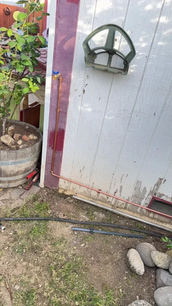 The raised hose bib and water line on the exterior wall.
