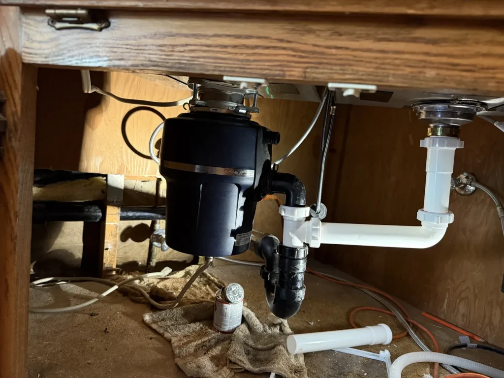 The plumbing connections below the kitchen sink.