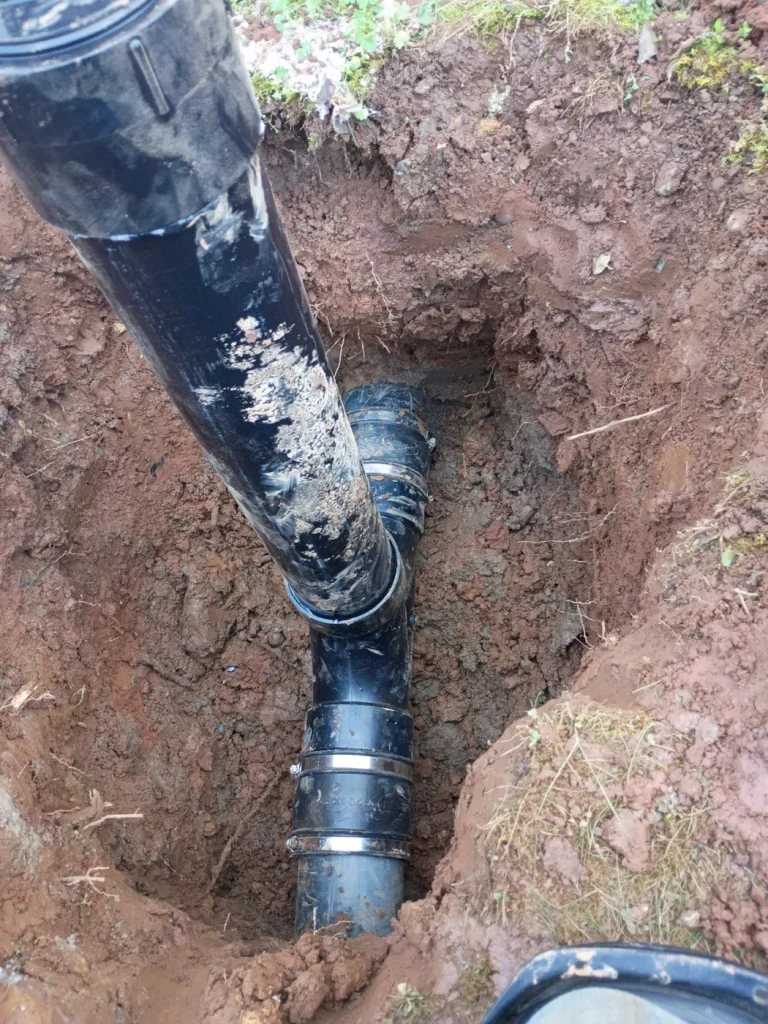 The cleanout and sewer-line connection exposed in the excavation.