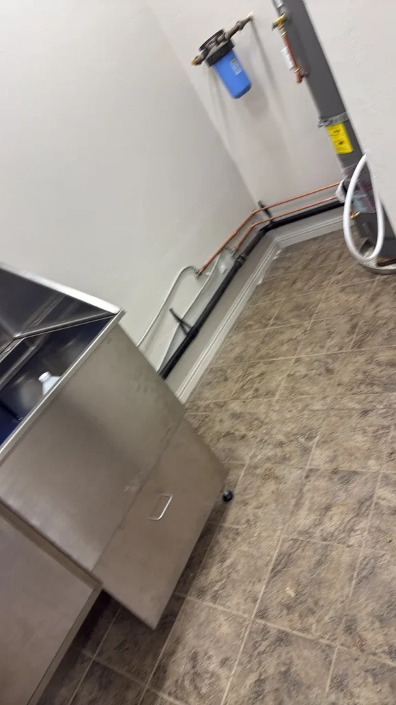 The wash area and pipework alongside the water heater.