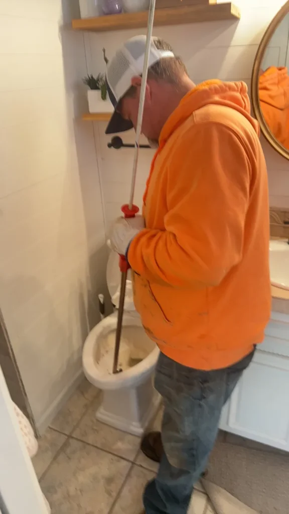 A Murray technician clearing the toilet with an auger.