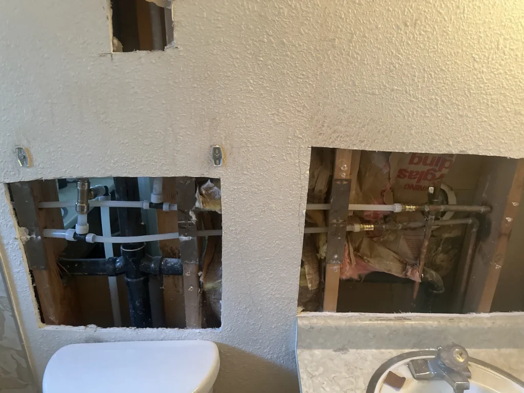 Exposed bathroom wall pipework during the whole-home repipe.