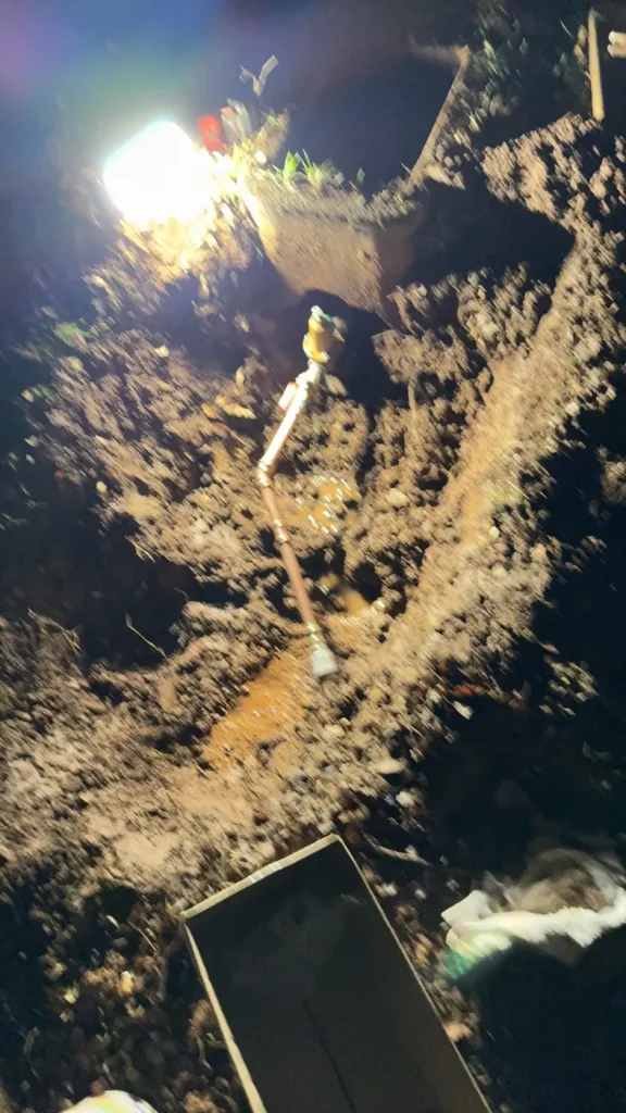 The exposed water-line repair area during evening work.